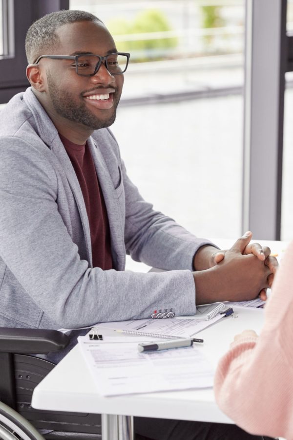 Handsome cheerful black male invalid in wheelchair involved in charity, meets with female investor, discuss main details, helps physically challenged people. People, health and business concept